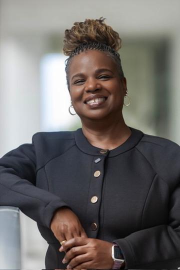 Susan L. Peterkin leaning on a railing, smiling.